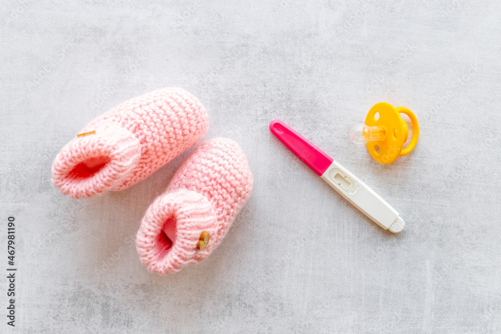 Pregnancy test and pink baby girl booties. Morherhood and pregnancy concept Pregnancy test and pink baby girl booties. Morherhood and pregnancy concept