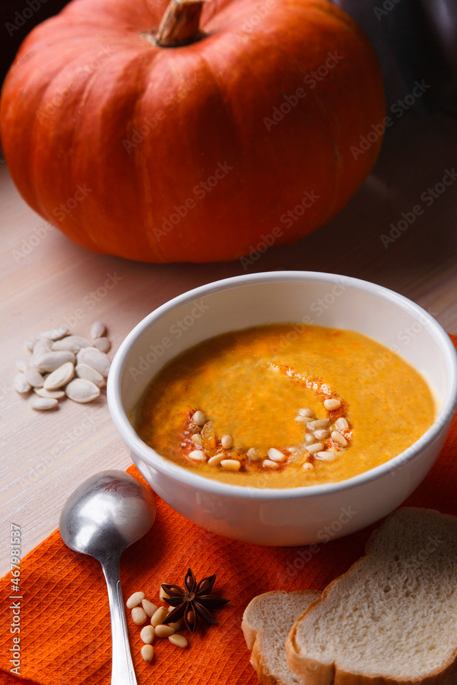 Homemade pumpkin soup with fresh pumpkin and bright orange kitchen cloth on white table Homemade pumpkin soup with fresh pumpkin and bright orange kitchen cloth on white table