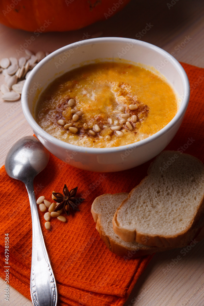 Homemade pumpkin soup with fresh pumpkin and bright orange kitchen cloth on white table Homemade pumpkin soup with fresh pumpkin and bright orange kitchen cloth on white table