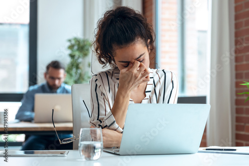 Tired business woman with headache looking uncomfortable while working with computer in the office