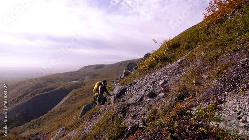 Tourist traveler with a backpack in the mountains. Khibiny mountains in an autumn day. Nice view of the mountains. Snow-capped mountain peaks in the sun