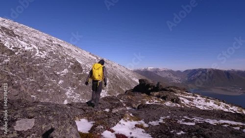 Tourist traveler with a backpack in the mountains. Khibiny mountains in an autumn day. Nice view of the mountains. Snow-capped mountain peaks in the sun