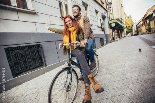 Happy young couple going for a bike ride on a autumn day in the city.