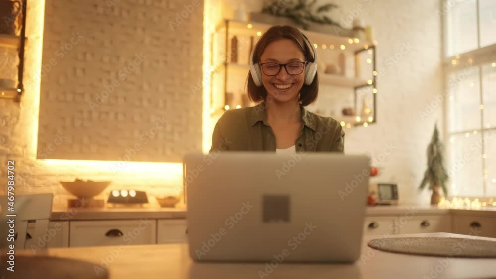 Young attractive woman indoors have a video call while sitting on the chair in the kitchen. Young lady talking on video conference online indoors. High quality 4k footage