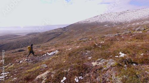 Tourist traveler with a backpack in the mountains. Khibiny mountains in an autumn day. Nice view of the mountains. Snow-capped mountain peaks in the sun