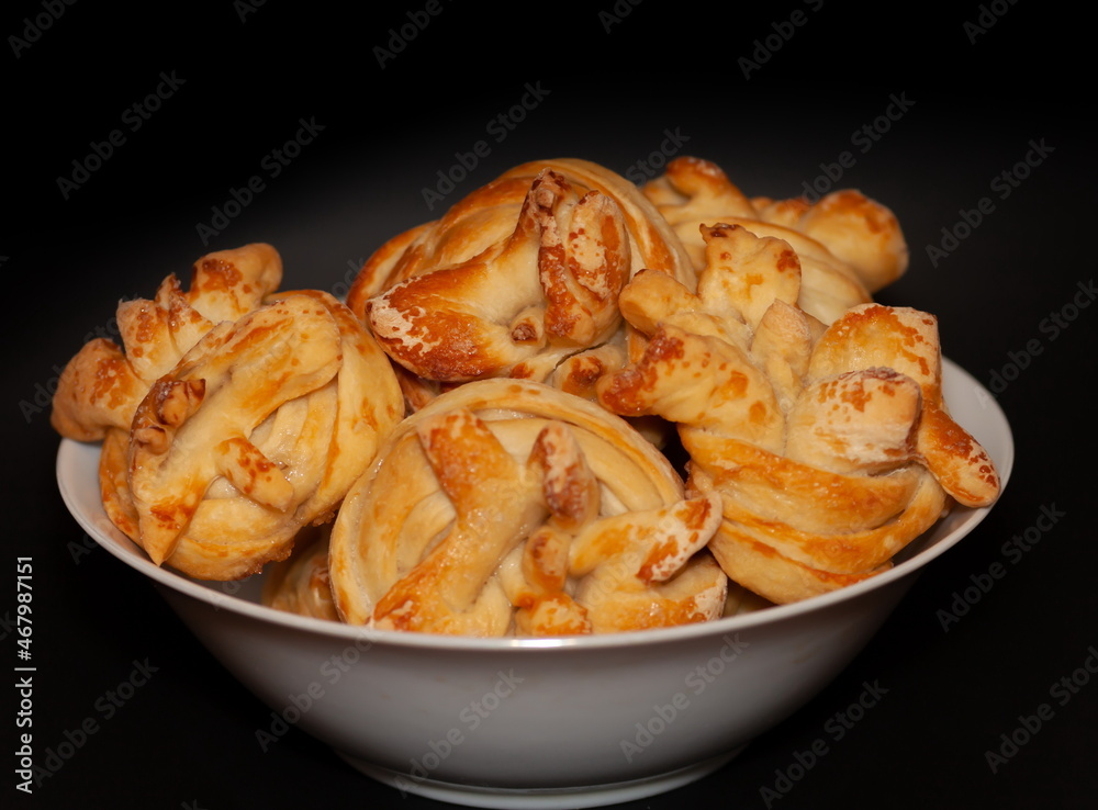 Homemade buns with sugar in a white ceramic plate on a black background Homemade buns with sugar in a white ceramic plate on a black background