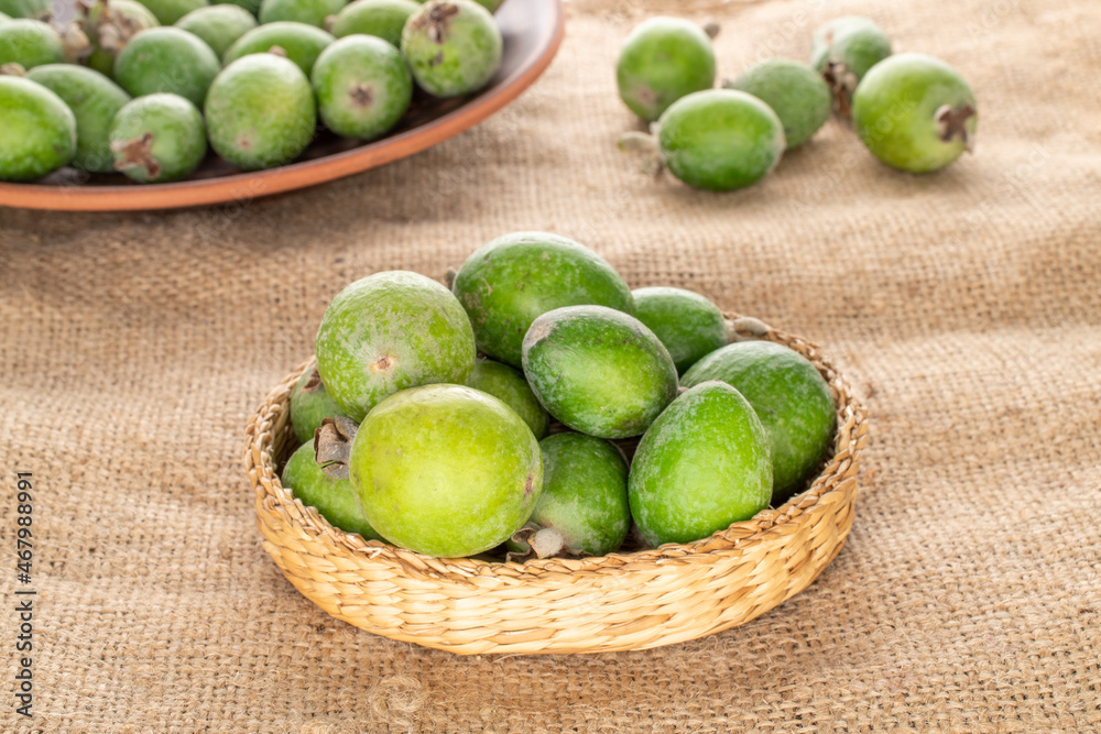 Several fragrant sweet feijoa fruits with straw dishes on sacking, close-up. Several fragrant sweet feijoa fruits with straw dishes on sacking, close-up.
