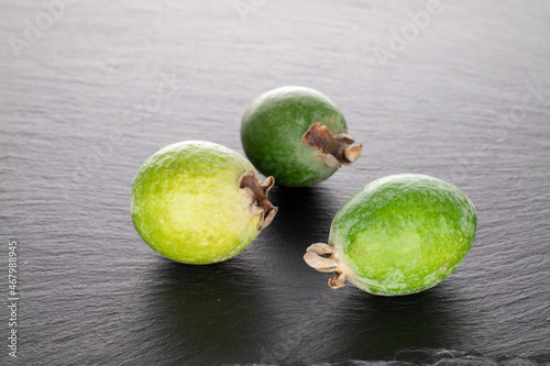 Three fragrant sweet feijoa fruits on a slate stone, close-up.