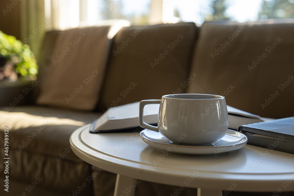 cup of coffee on round white table in living room by leather sofa with open bible book