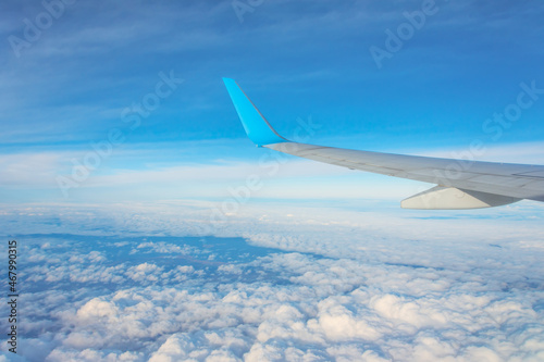 Wing of an airplane flying above the clouds. Looks at the sky from the window of the plane, using airtransport to travel.