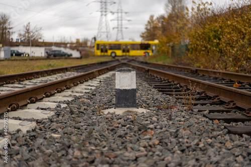 Photo of railway tracks connected at one distant point. Bus in the background. Railroad pole marker. photo