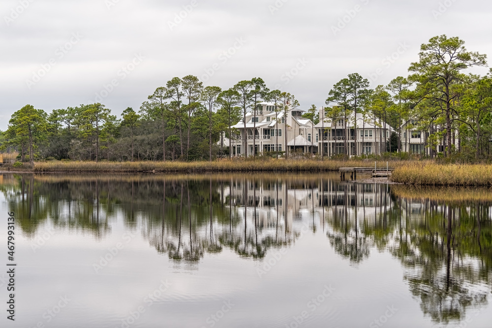 Western lake in Seaside, Florida Gulf of Mexico on cloudy day with lake house reflection and pine trees in winter