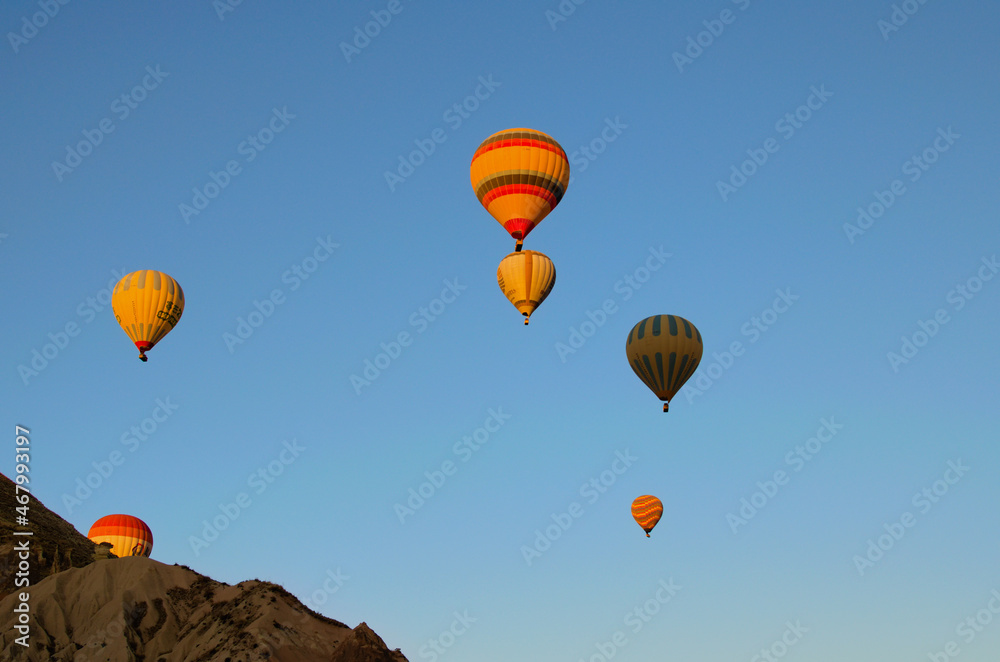Obraz premium Goreme, Turkey-October 9,2021:Air balloons festival in Cappadocia. Few hot air balloons against colorful vibrant sky. Picturesque nature landscape in the background