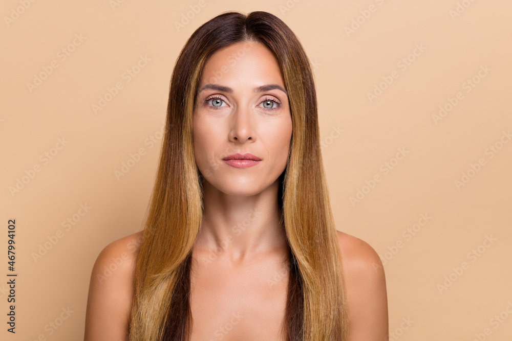 Naklejka premium Portrait of attractive candid healthy long-haired woman with clear pure fresh skin isolated over beige pastel color background