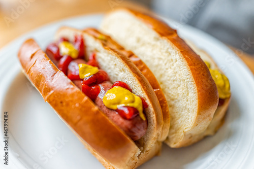 Hot dog sausage cooked prepared on brioche bun with ketchup and mustard condiments macro closeup showing detail and texture