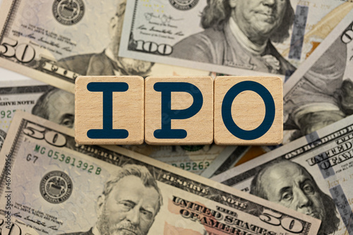 ipo (initial public offering) theme. wooden cubes with the acronym ipo, on the background of dollar bills. ipo business concept