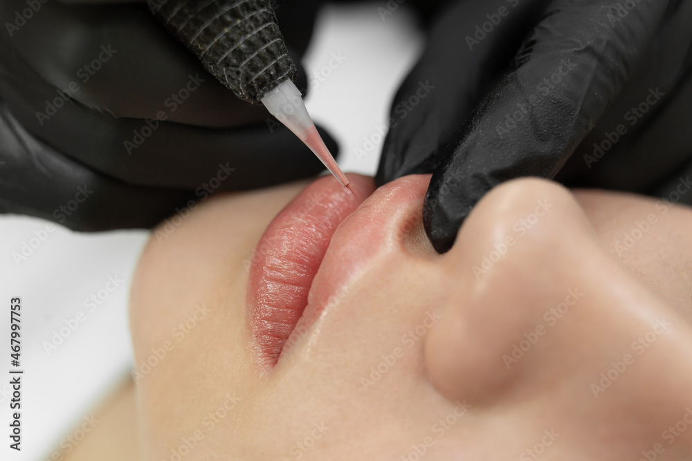 Close-up of the permanent makeup procedure. Lip makeup in the cosmetologist's salon. - obrazy, fototapety, plakaty 