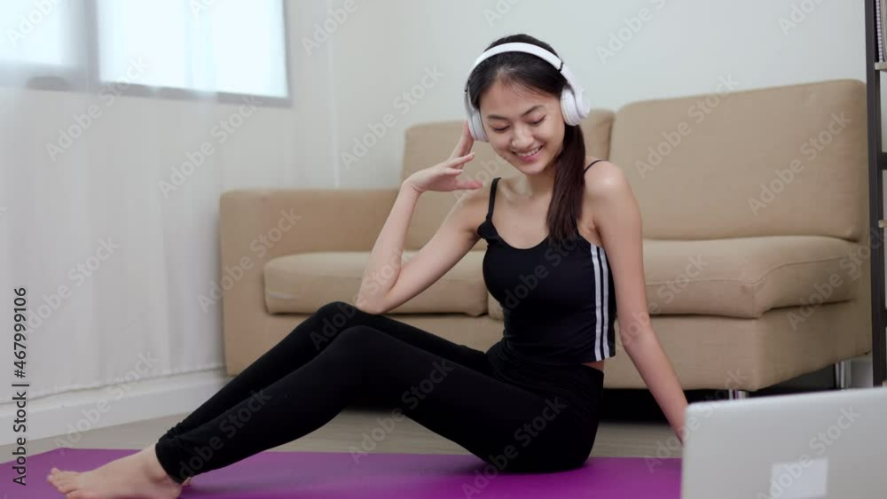 Young beautiful asian woman sitting pose smiling to camera. Cheerfully sporty female workout and exercise wearing sport wear at home. Charming woman fitness training and stretching on yoga mat. Young beautiful asian woman sitting pose smiling to camera. Cheerfully sporty female workout and exercise wearing sport wear at home. Charming woman fitness training and stretching on yoga mat.