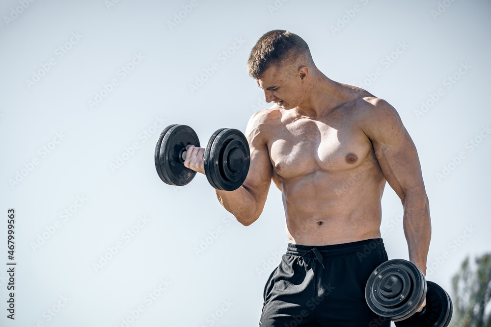 Athletic sporty bodybuilder posing outdoor. Strong muscular man standing outdoor on landscapes.