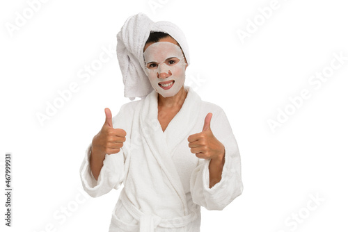 Woman with wet sheet mask on face showing thumbs up gesture, white isolated background. photo