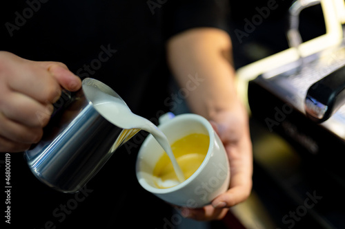 Barista making latte in cup with milk. Hand of professional barista making cappuccino coffee pouring milk.