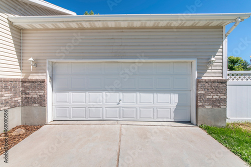 Attached garage with white sectional door and concrete driveway