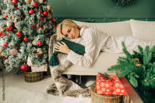 Frustrated depressive sad sick woman in pajamas lies on the sofa in christmas alone. Holidays alone at home.