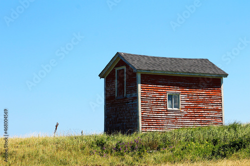 An old red barn on a grassy hill