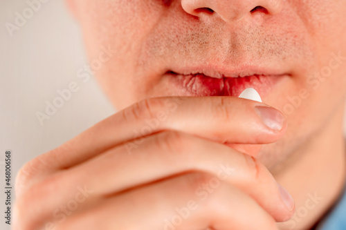 A young сaucasian man takes a pill. Man making medicine at home, closeup