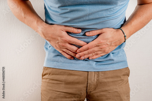 A man is holding on to a sick stomach. The concept of abdominal pain