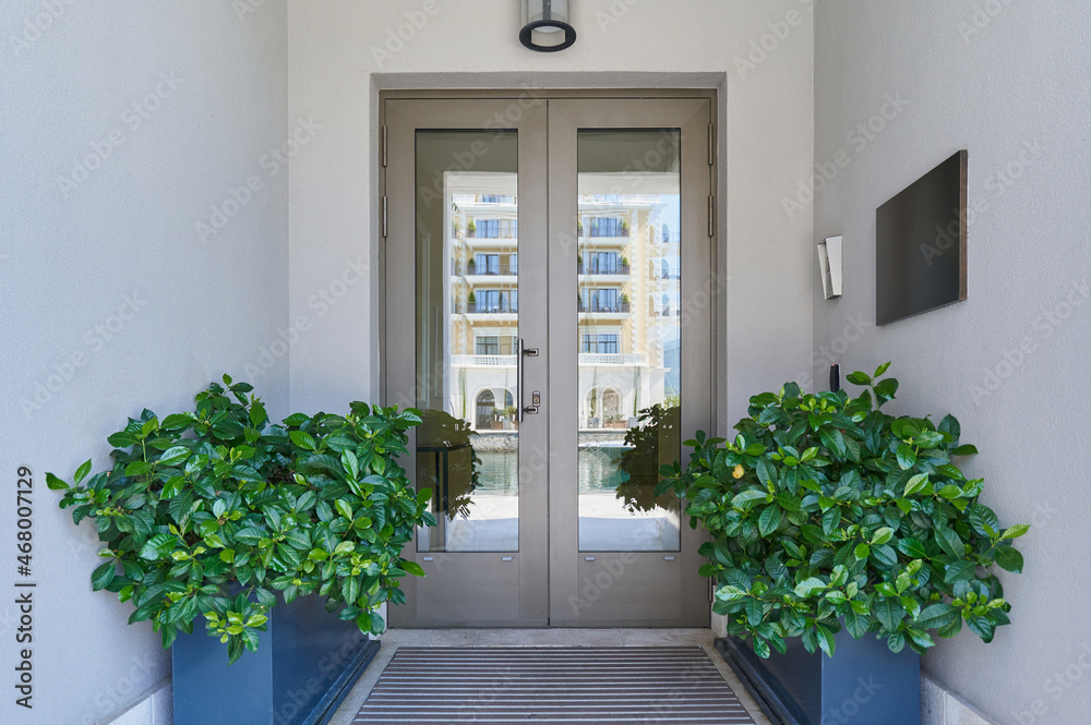 Building entrance with glass door and plants Building entrance with glass door and plants