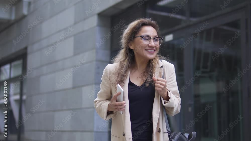 Cheerful business woman dancing smartphone in hand, satisfied with mobile app Cheerful business woman dancing smartphone in hand, satisfied with mobile app