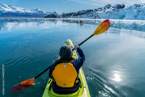 A female kayaker paddles through Glacier Bay National Park, Alaska. 