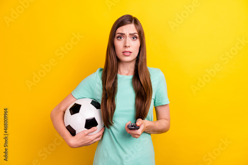 Photo of sad brunette hairdo young lady hold ball switch tv wear teal t-shirt isolated on yellow color background © deagreez