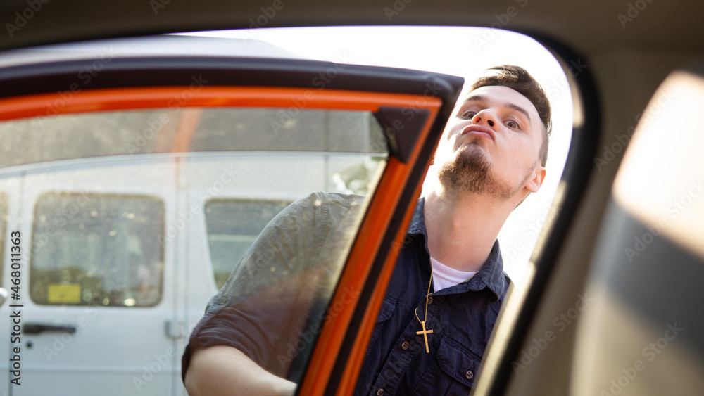 Naklejka premium man looking into orange car