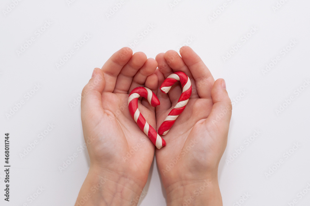 two caramel plasticine canes in the hands of a child on a white background two caramel plasticine canes in the hands of a child on a white background