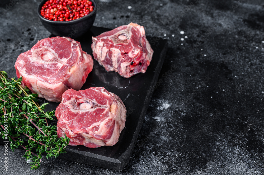 Raw lamb neck meat on a marble board..Black background. Top view. Copy space