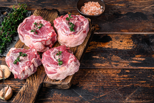 Raw mutton lamb neck meat on a butcher board with cleaver. Dark wooden background. Top view. Copy space photo