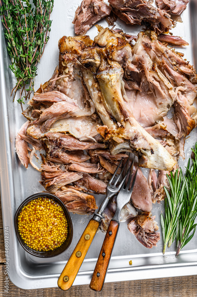 Baked pork knuckle eisbein meat on a baking pan with herbs. Wooden background. Top view