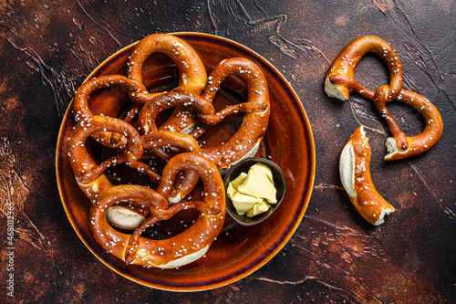 Obraz na plátně Freshly baked homemade pretzel with salt on a rustic plate