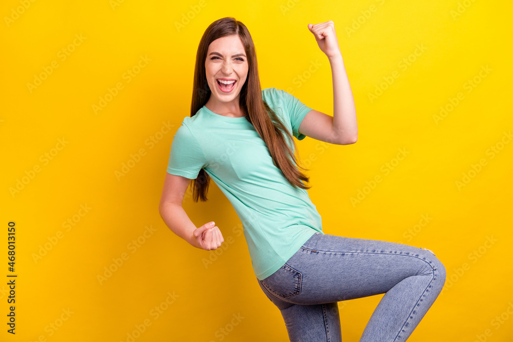Photo of hooray brunette hairdo young lady fists hands wear teal t-shirt isolated on yellow color background Photo of hooray brunette hairdo young lady fists hands wear teal t-shirt isolated on yellow color background
