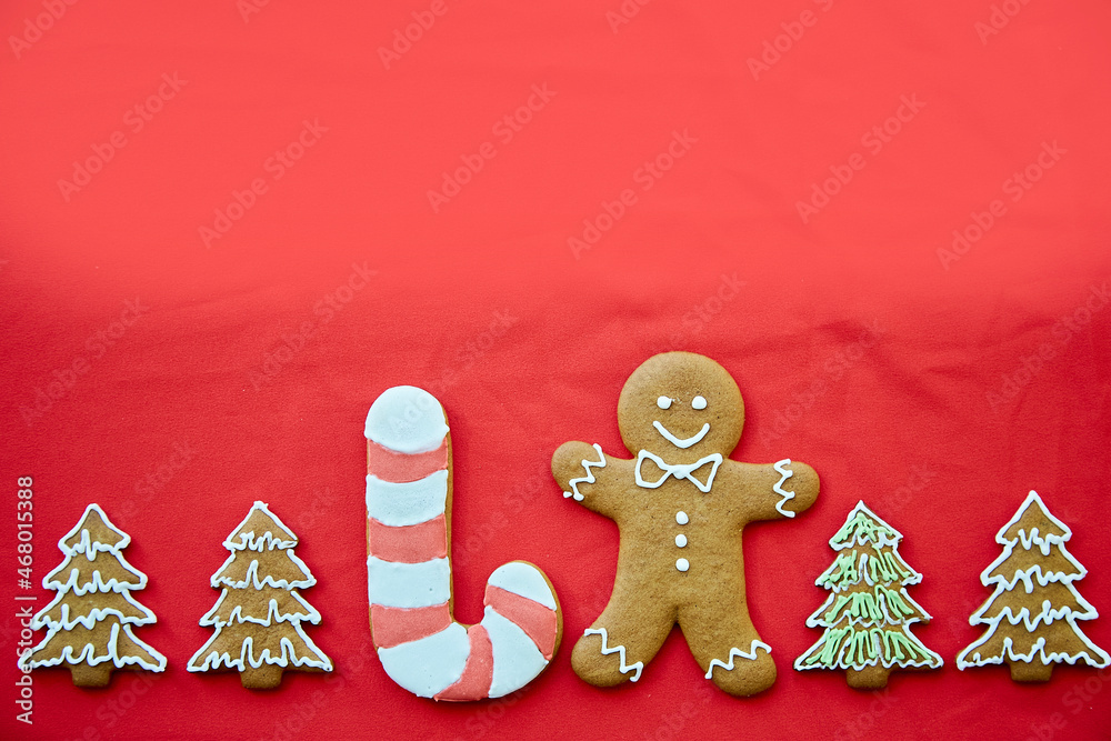 Fototapeta Christmas handmade gingerbread cookies with copy space on red fabric background. Homemade baking background. Festive card with aesthetic Christmas atmosphere. Merry Christmas and home coziness