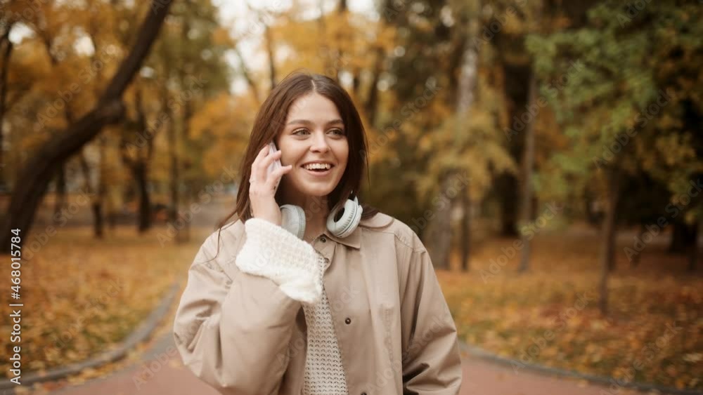 Pretty laughing girl with smartphone has a good time in autumn weekend. Happy young woman talking on mobile phone in autumn park Pretty laughing girl with smartphone has a good time in autumn weekend. Happy young woman talking on mobile phone in autumn park