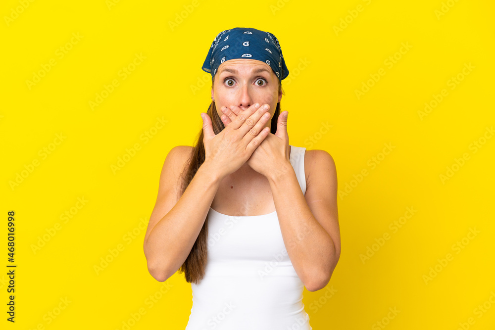 Young English woman isolated on yellow background covering mouth with hands Young English woman isolated on yellow background covering mouth with hands