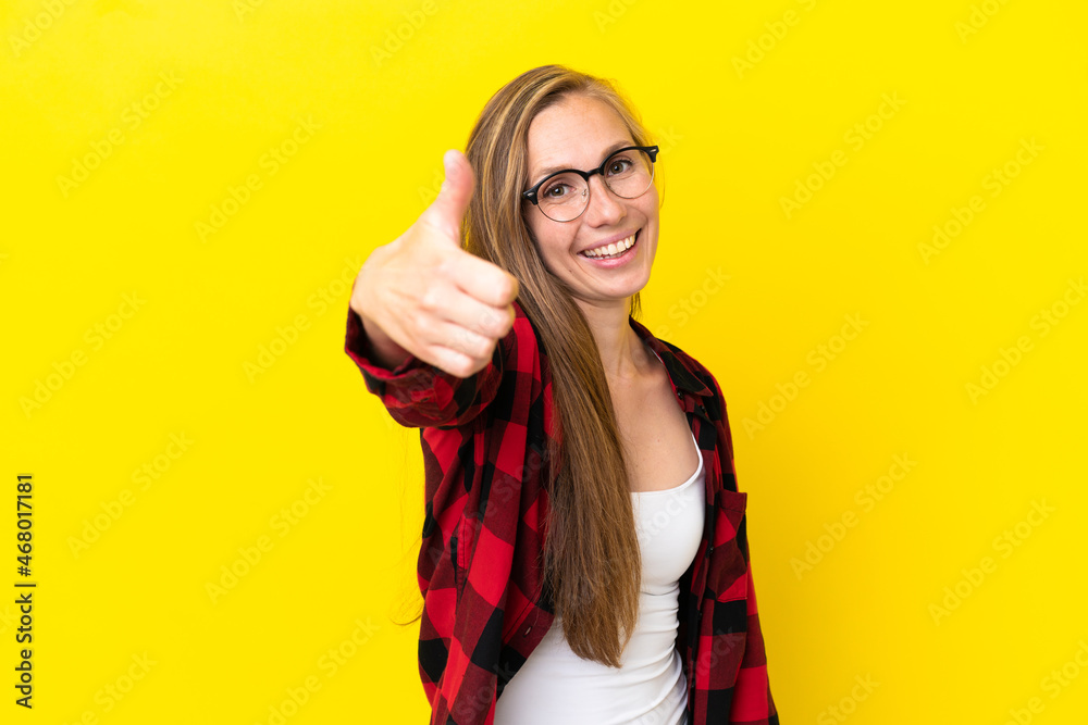 Young English woman isolated on yellow background with thumbs up because something good has happened