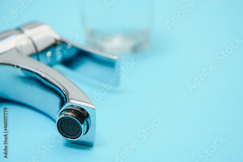 Single handle water tap on light blue background, closeup