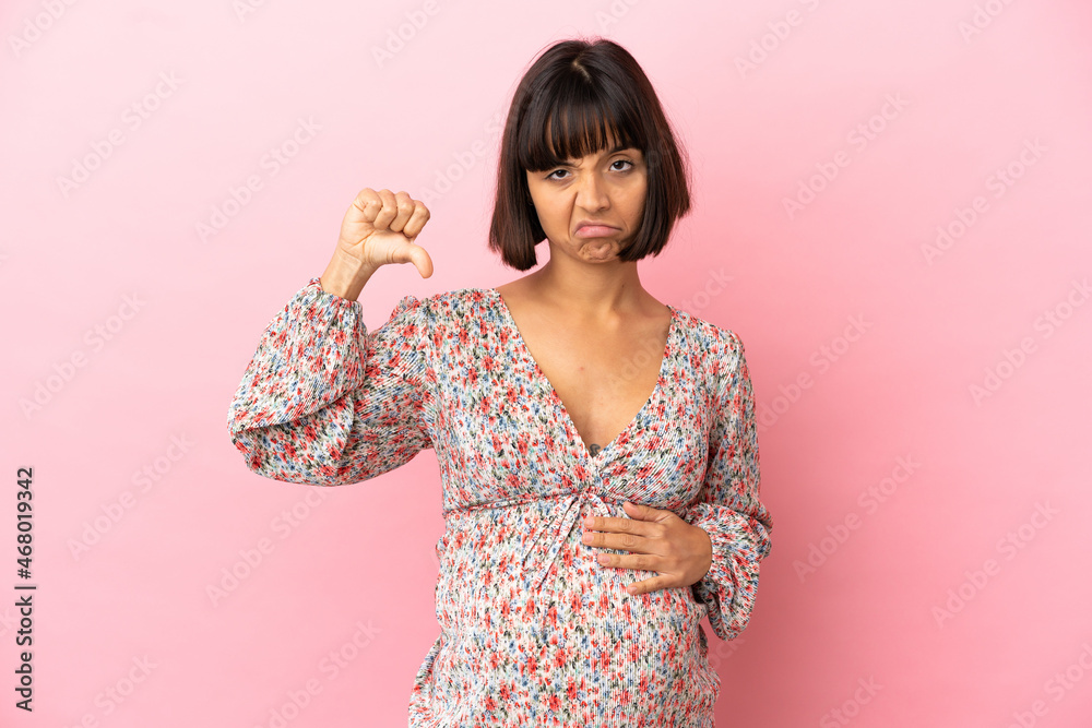 Young pregnant woman over isolated pink background showing thumb down with negative expression Young pregnant woman over isolated pink background showing thumb down with negative expression