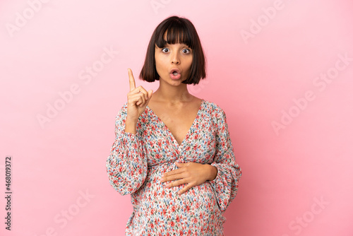 Young pregnant woman over isolated pink background intending to realizes the solution while lifting a finger up © luismolinero