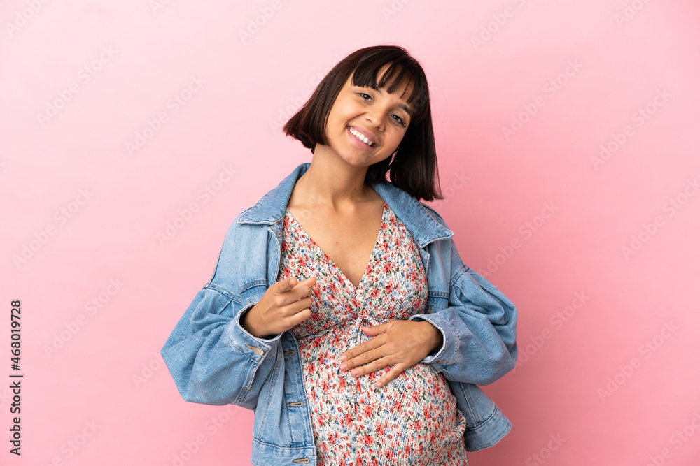 Young pregnant woman over isolated pink background pointing front with happy expression Young pregnant woman over isolated pink background pointing front with happy expression