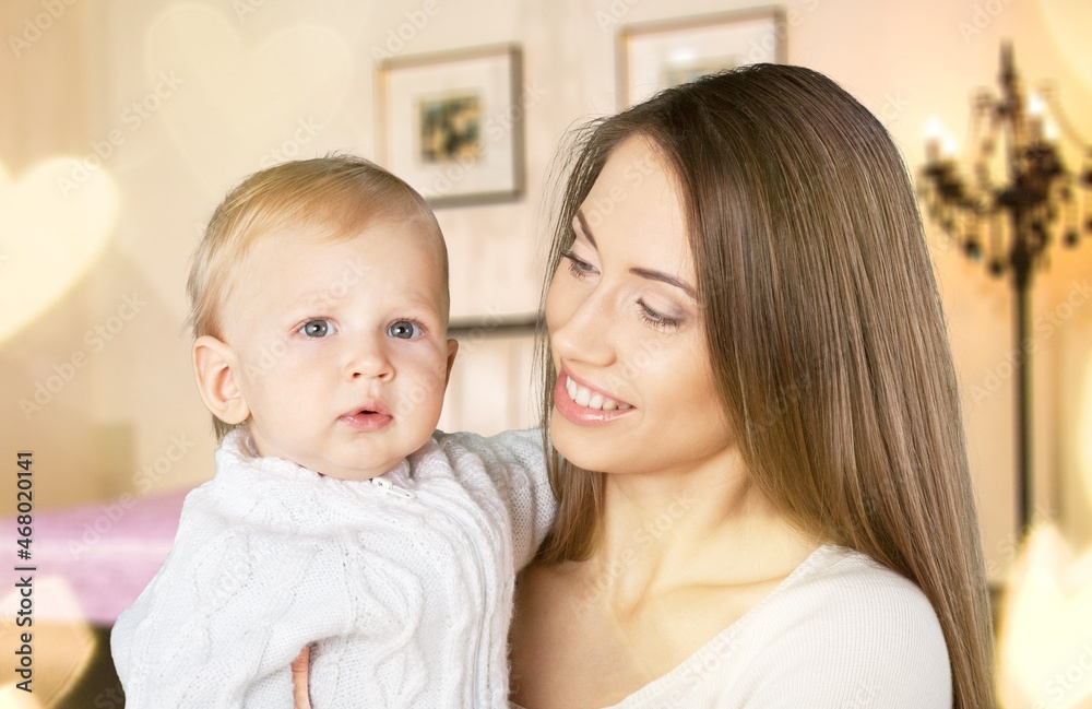 Young mother hugging her little child, they sitting near window and smiling. Young mother hugging her little child, they sitting near window and smiling.